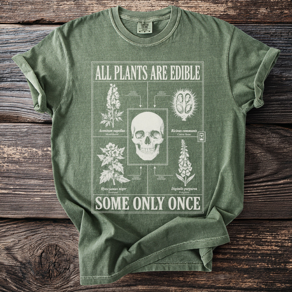 Green t-shirt with a graphic of toxic plants and a skull, reading "All Plants Are Edible, Some Only Once."