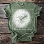 Green t-shirt with graphical print and text "i live in your walls."