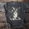 Corgi wearing a witch hat with a broom and moon graphic on a dark t-shirt.