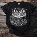 Black t-shirt graphic with open book, tarot cards, and celestial designs.
