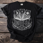 Black t-shirt graphic with open book, tarot cards, and celestial designs.