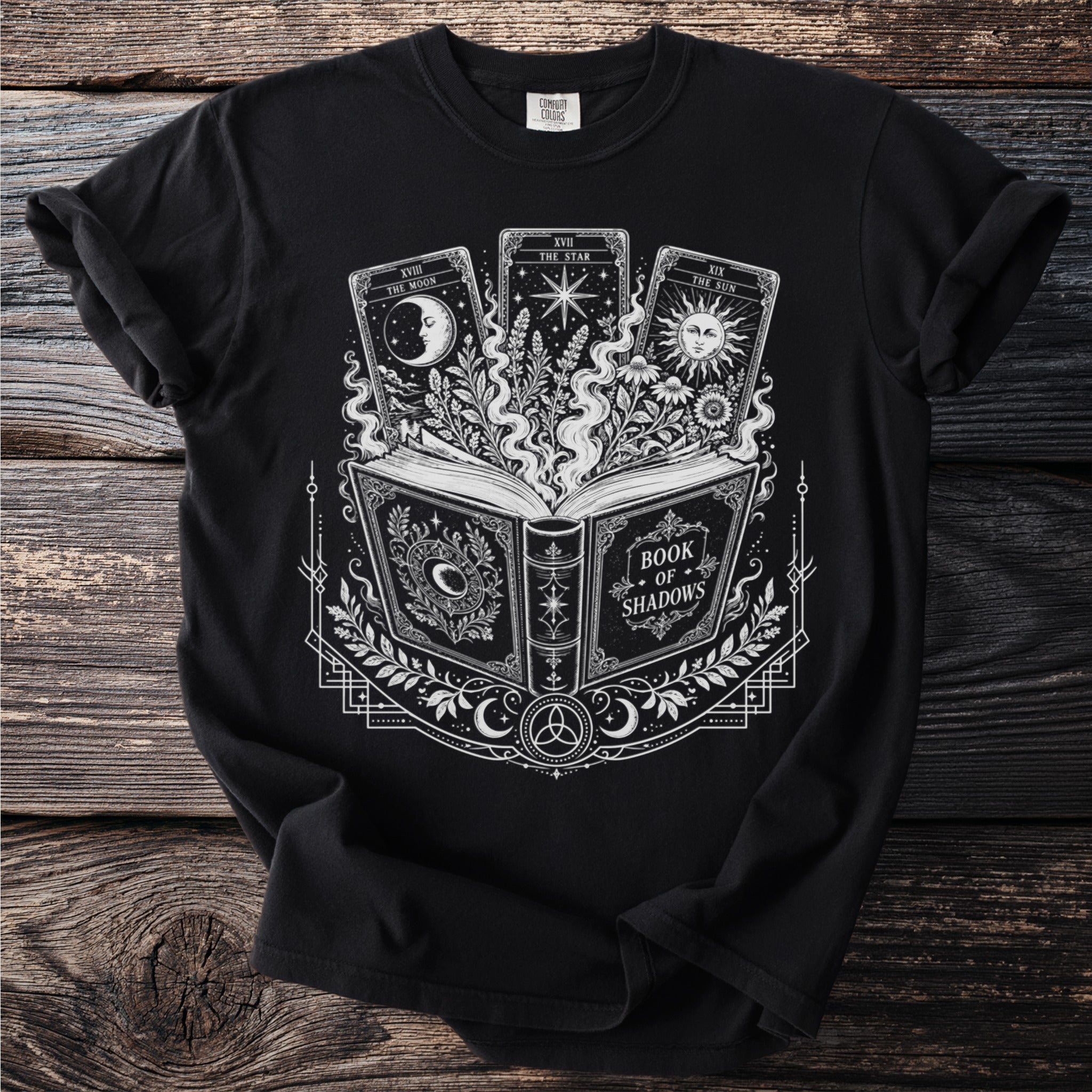 Black t-shirt graphic with open book, tarot cards, and celestial designs.