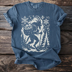 Blue t-shirt with white graphic of Krampus surrounded by snowflakes and trees.