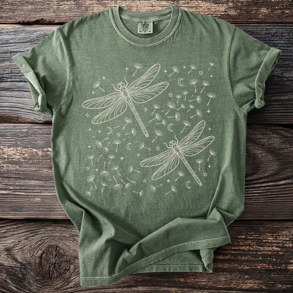 Green t-shirt with two outline dragonflies and dandelion seeds.