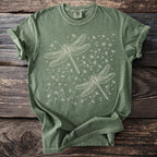 Green t-shirt with two outline dragonflies and dandelion seeds.