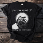 Black t-shirt with a close-up of a pigeon and text "patron saint of minding my own business".