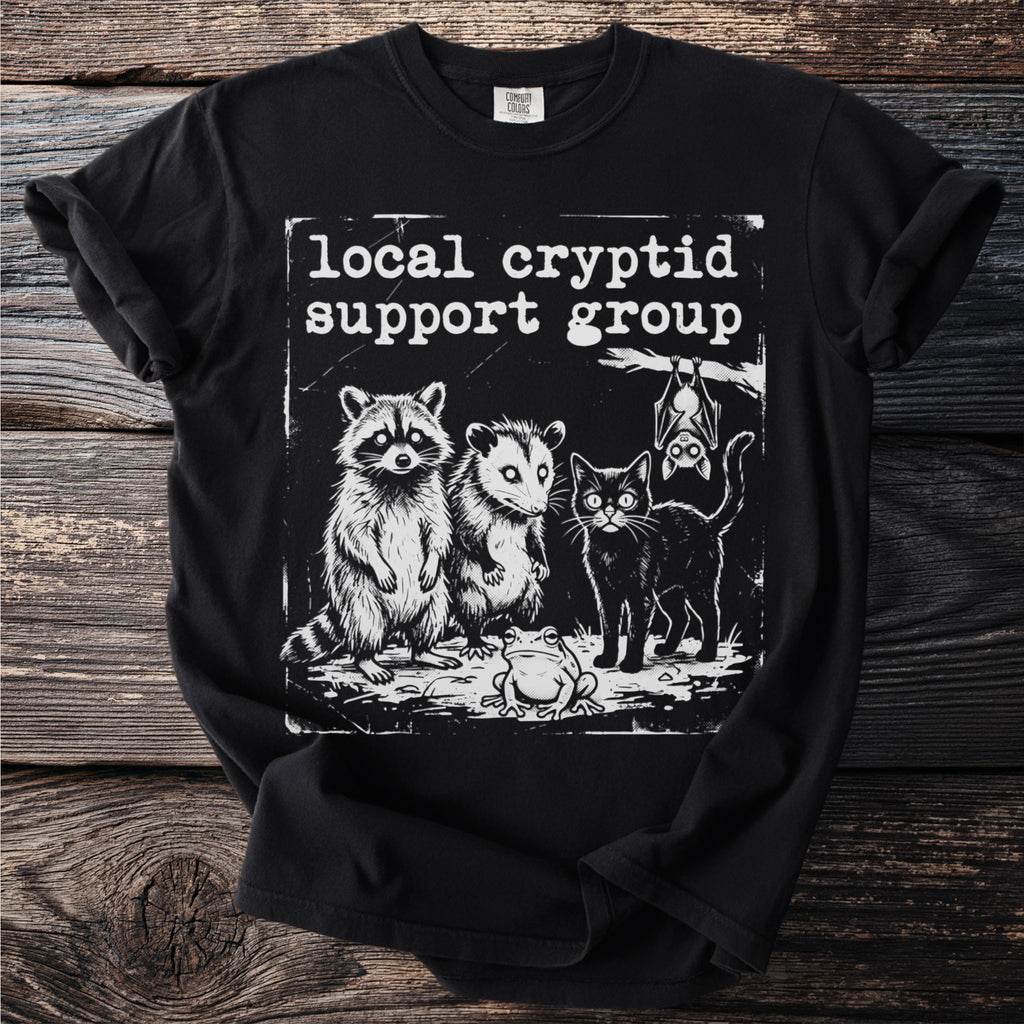 Black t-shirt with "Local Cryptid Support Group" text and raccoon, opossum, cat, frog, and bat illustration.