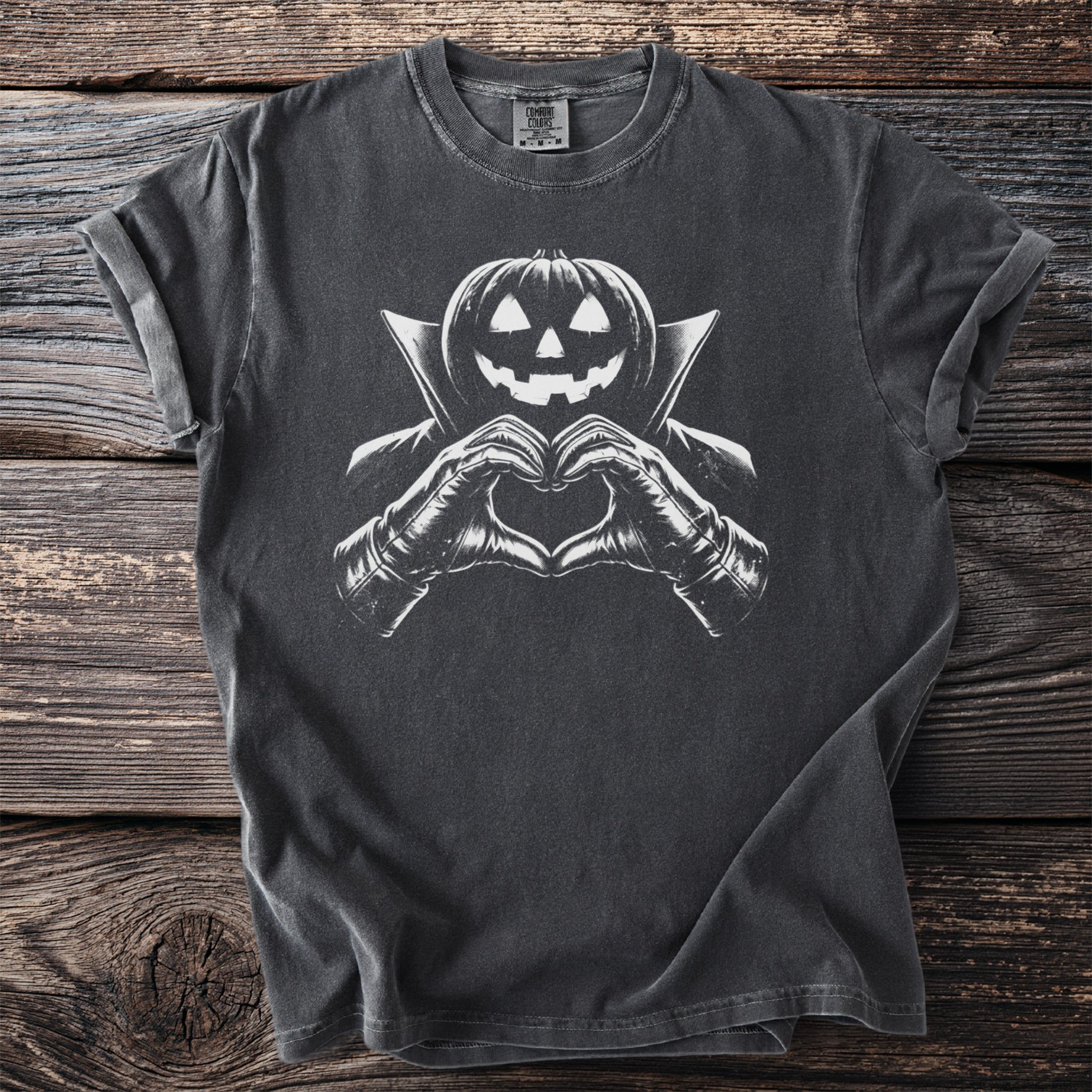 Dark t-shirt with a white graphic of a jack-o'-lantern in a cape making a heart shape.
