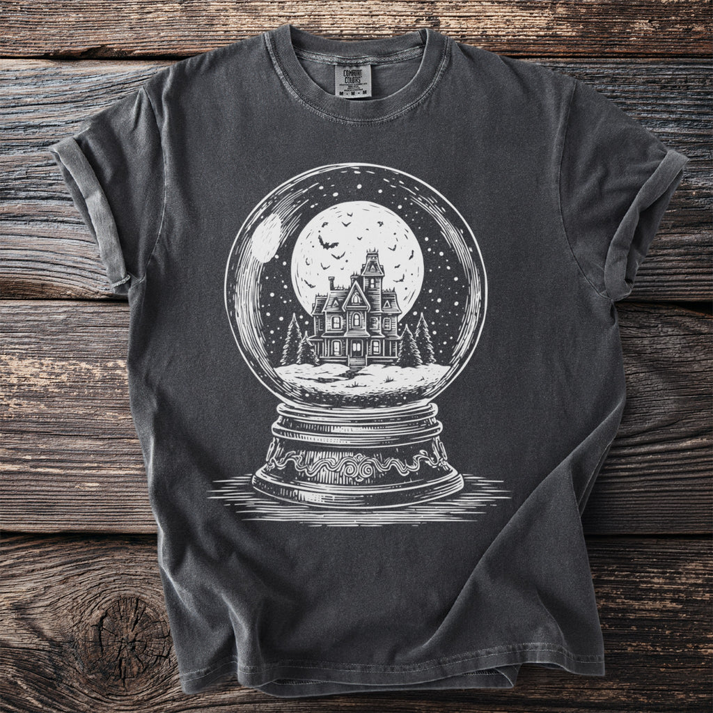 Dark t-shirt with white graphic of haunted house in a snow globe under a full moon.