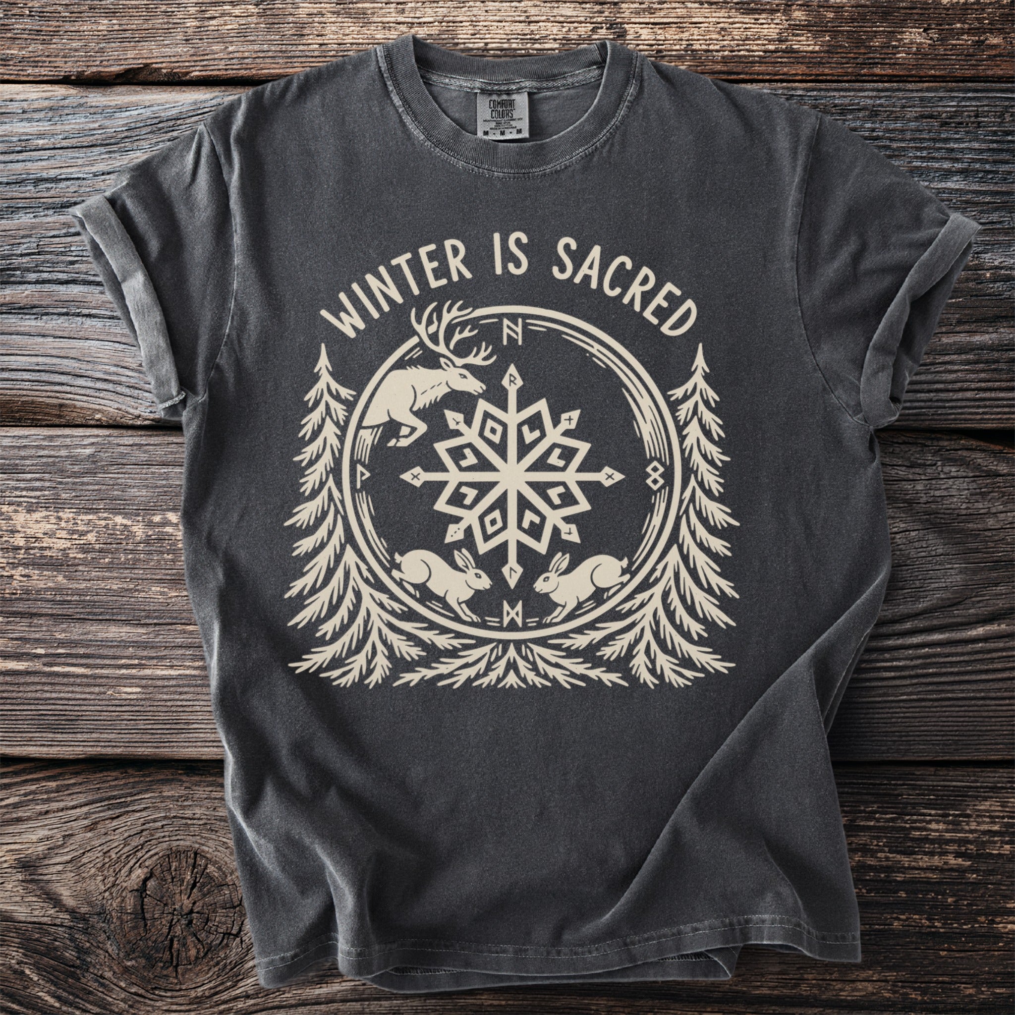 Pepper t-shirt with "WINTER IS SACRED" above a stag, two hares, pines and a snowflake.