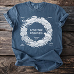 Blue t-shirt with white graphic of "Love the Unloved" text surrounded by reptiles and plants.