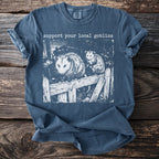 Blue t-shirt with two opossums on a wooden fence and text "support your local goblins".