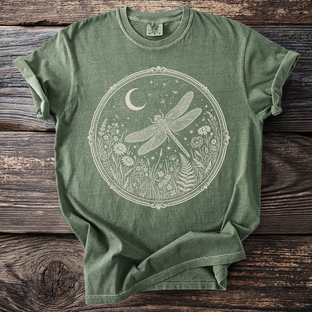 Green t-shirt with white dragonfly and meadow graphic within an oval frame.