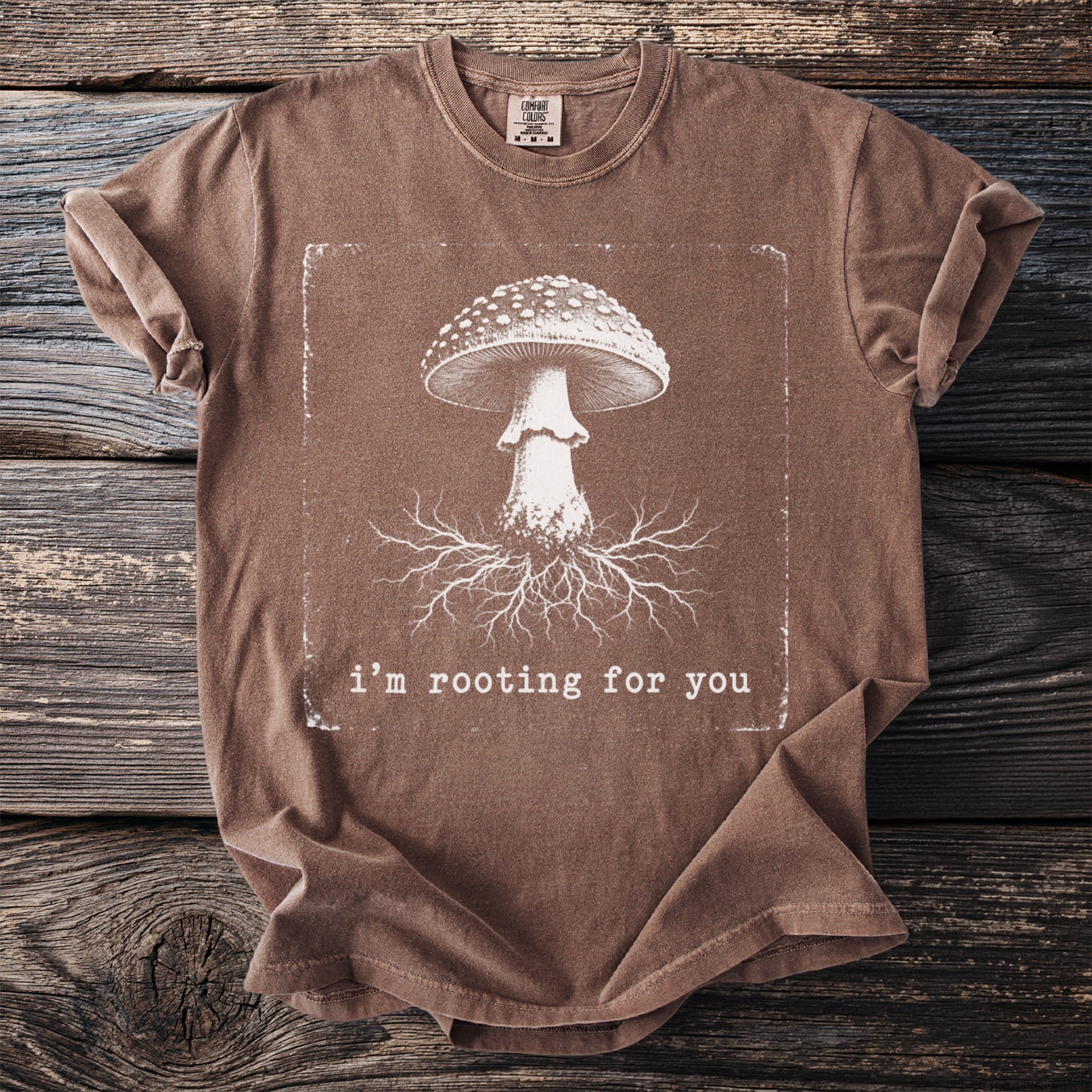 Brown t-shirt with a mushroom and roots graphic and text "i'm rooting for you".