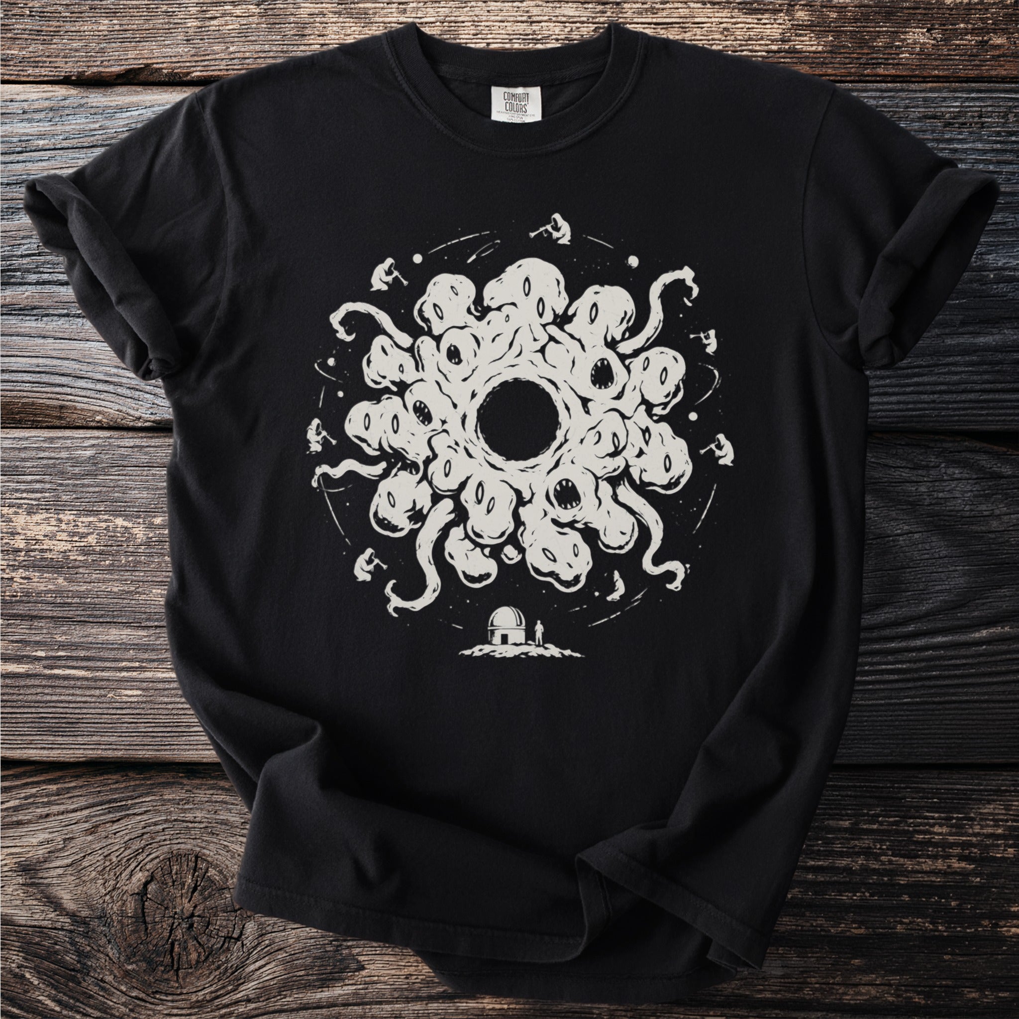 Black t-shirt with a white graphic of a creature with many eyes and tentacles surrounding a black hole.