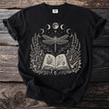 Black t-shirt with occult-themed illustration: dragonfly, open book, herbs, potions