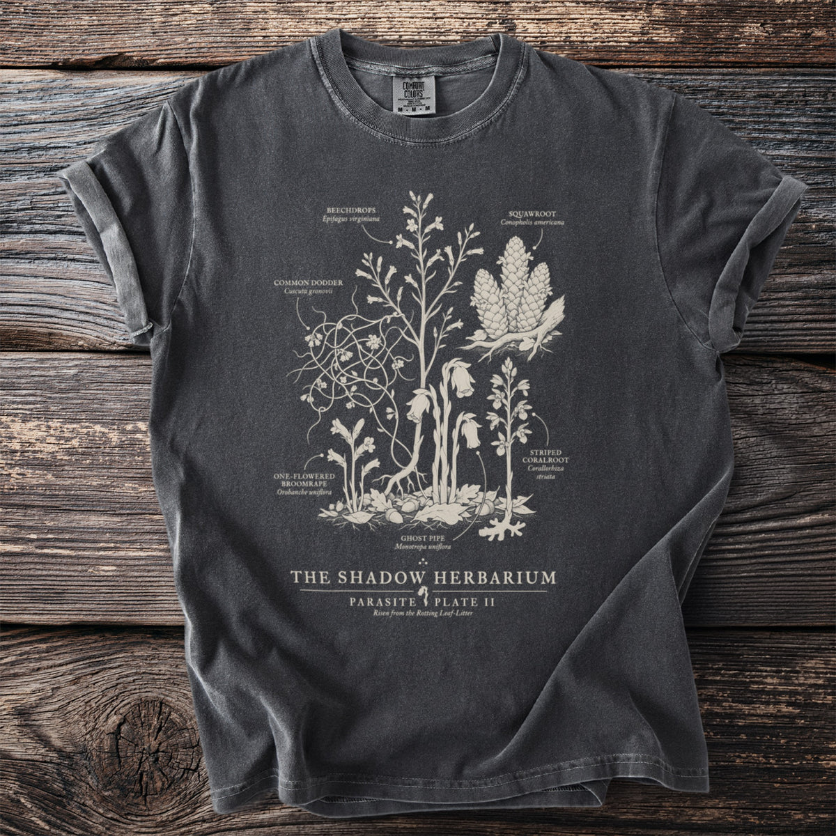 Dark t-shirt with botanical illustration of parasitic plants labeled "The Shadow Herbarium".