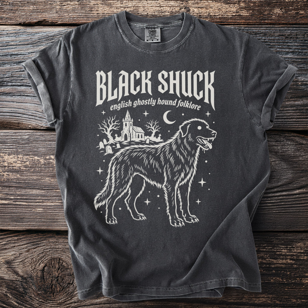 Dark gray t-shirt featuring a ghostly hound, graveyard, and church graphic with "BLACK SHUCK" text.