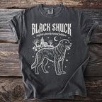Dark gray t-shirt featuring a ghostly hound, graveyard, and church graphic with "BLACK SHUCK" text.
