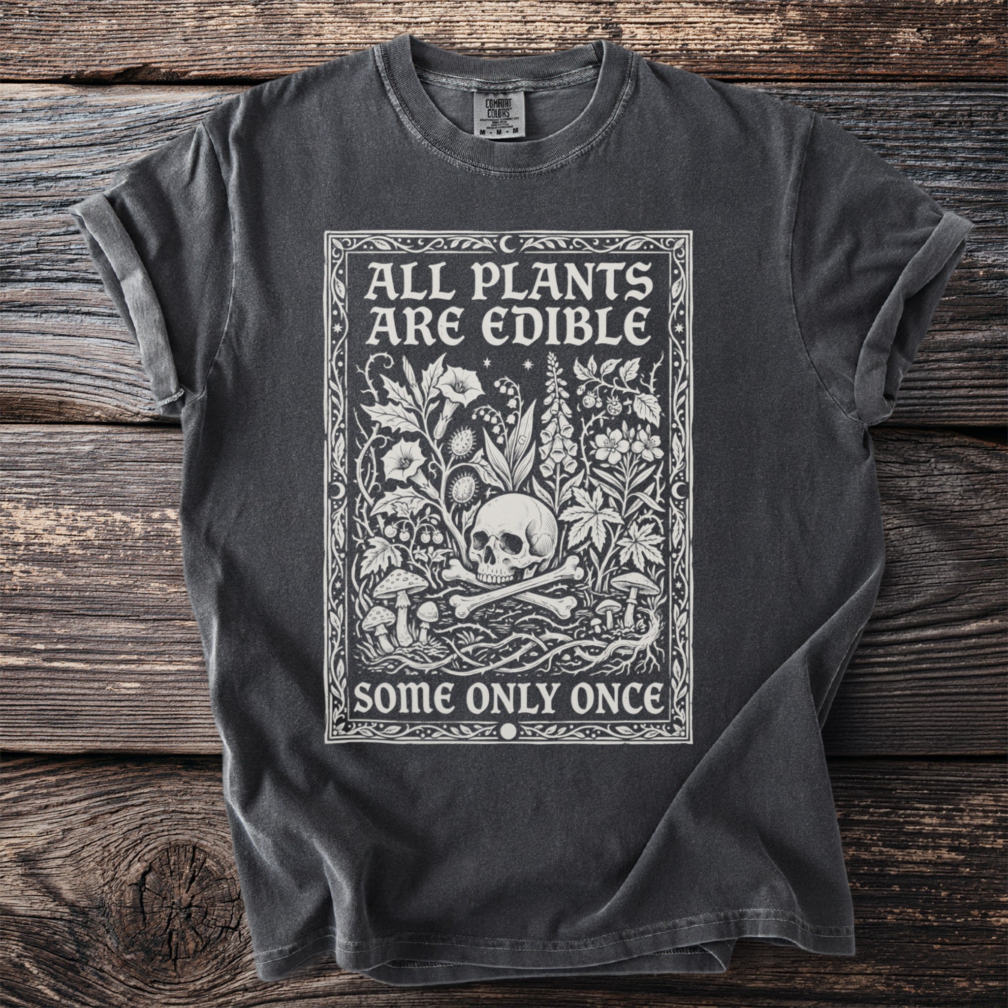 Dark grey t-shirt with white text and illustration of skull, bones, and plants.