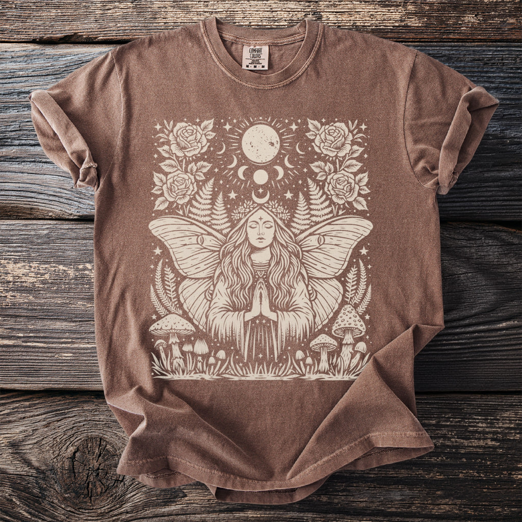 Brown t-shirt with tan linocut design of a woman with butterfly wings, moon phases, and mushrooms.