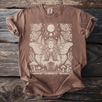 Brown t-shirt with tan linocut design of a woman with butterfly wings, moon phases, and mushrooms.