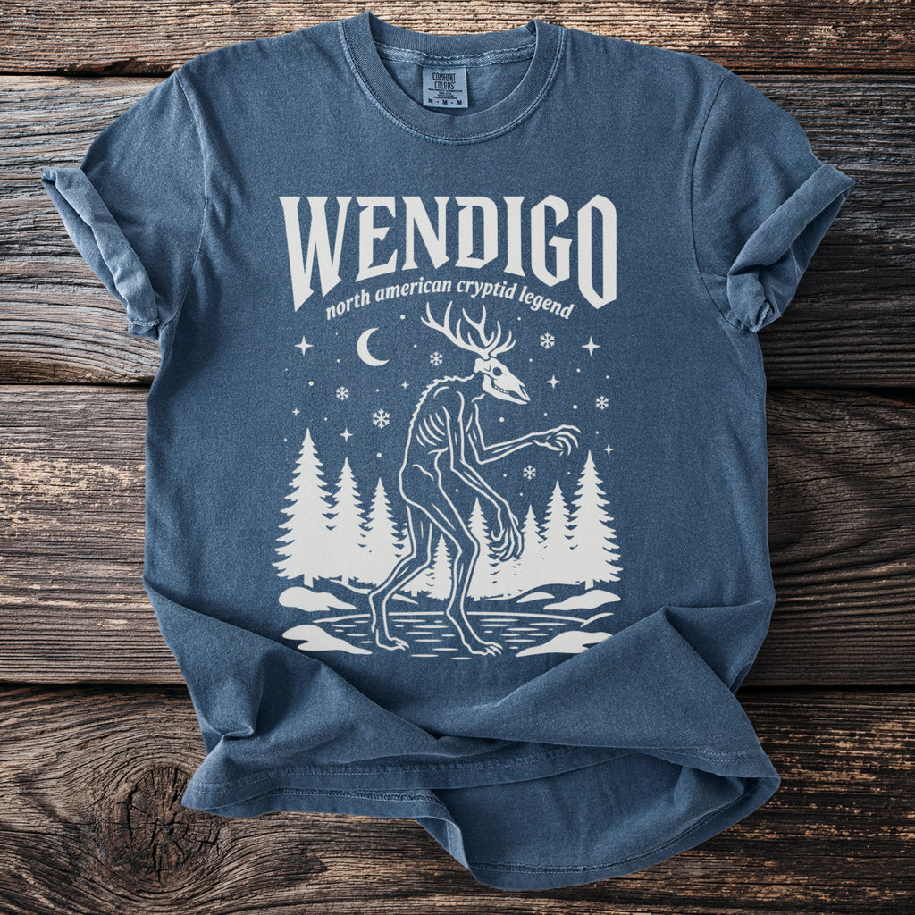 Blue t-shirt with white print of a Wendigo and forest scene.