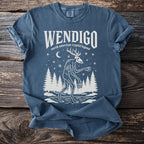 Blue t-shirt with white print of a Wendigo and forest scene.
