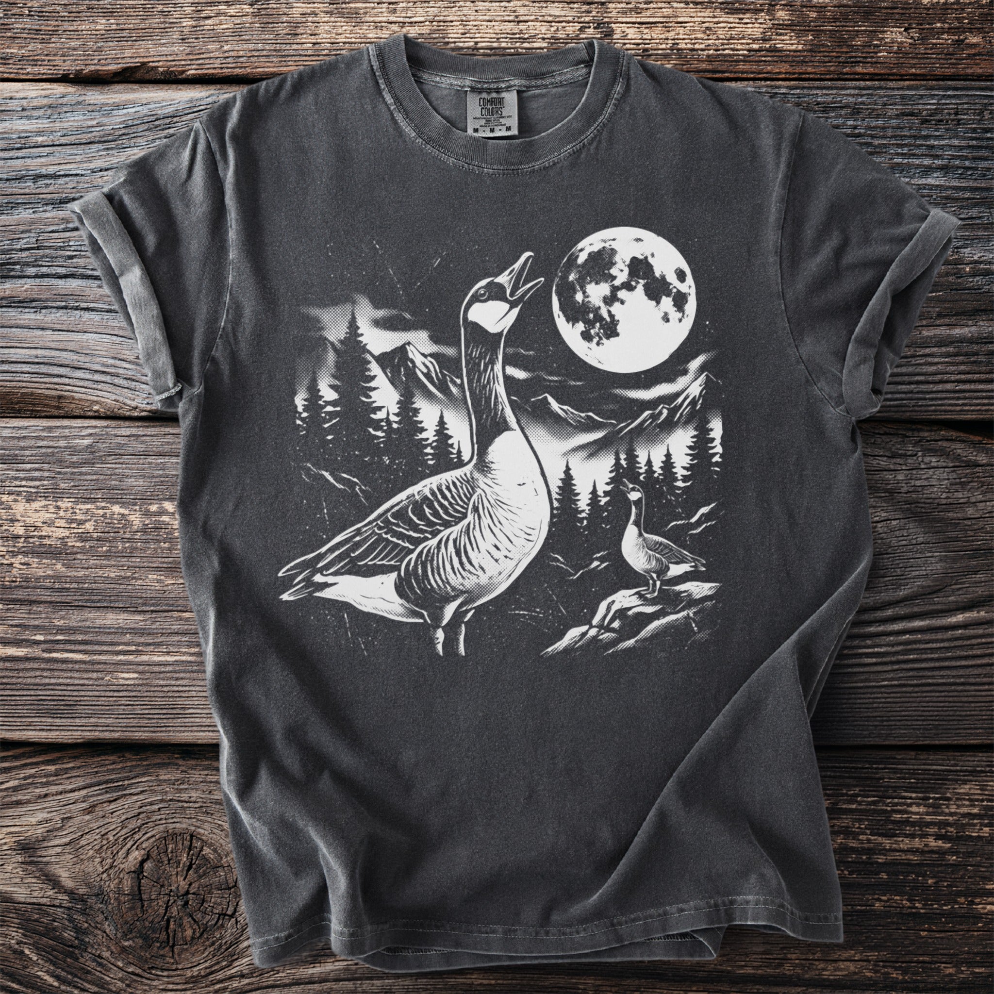 Graphic t-shirt with geese, mountains, trees, and a full moon at night.