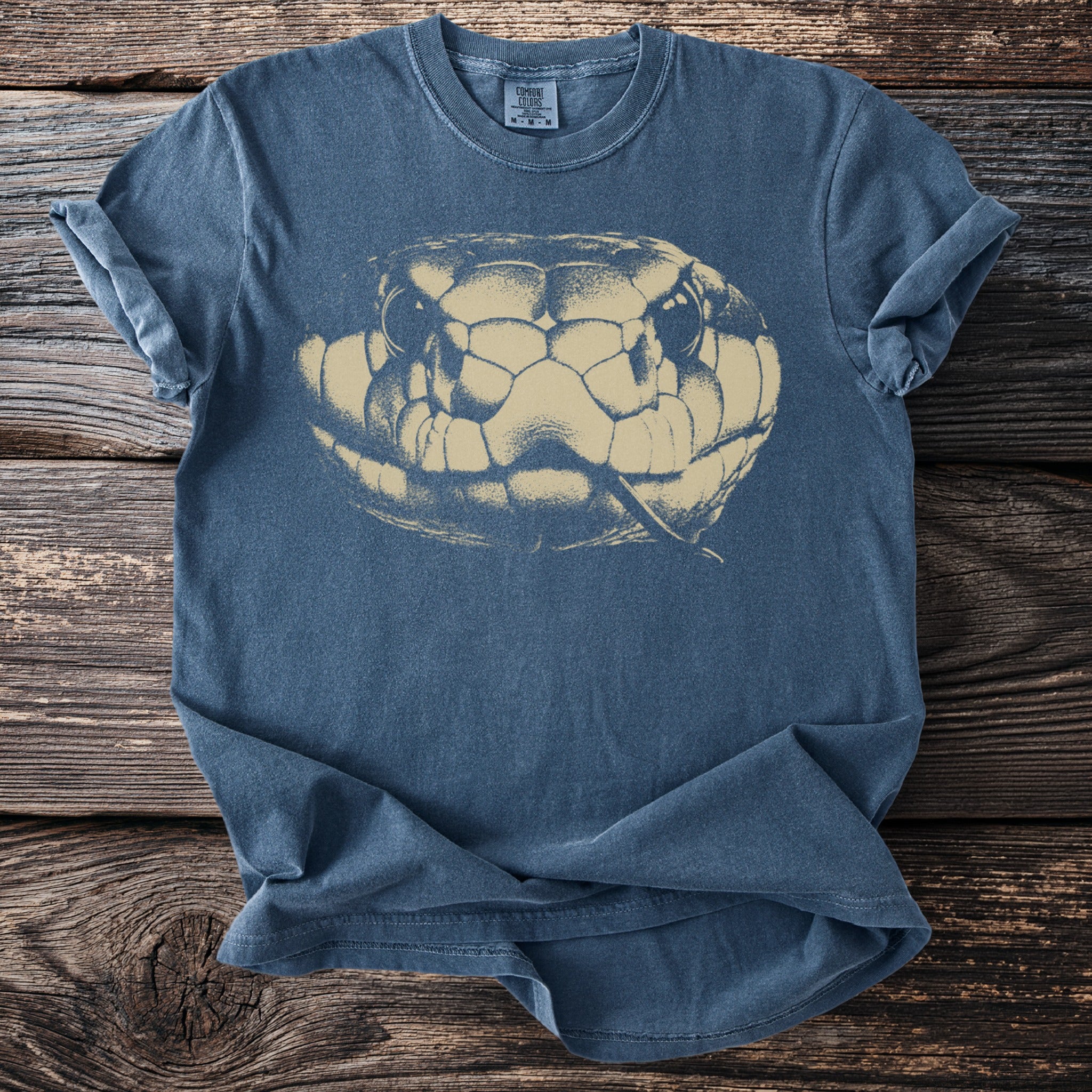 Blue t-shirt with a faded beige snake head graphic and Comfort Colors tag.