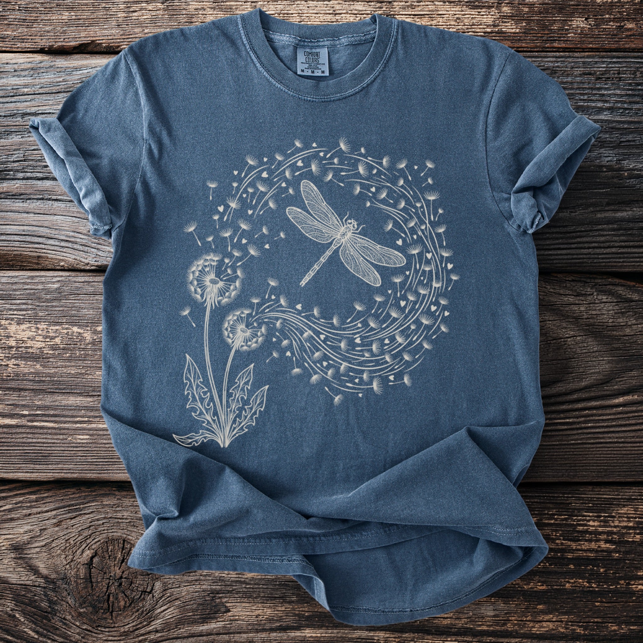 Blue t-shirt with a white line drawing of a dragonfly and dandelions.