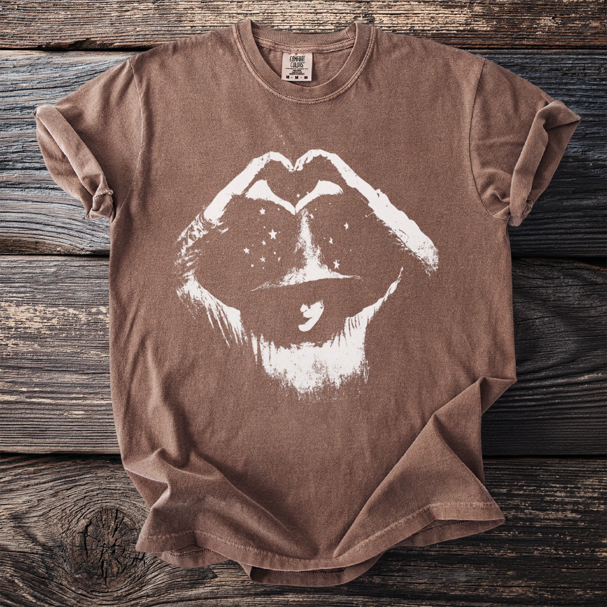 Brown t-shirt with graphic of lips and starry eyes formed by hands making a heart.