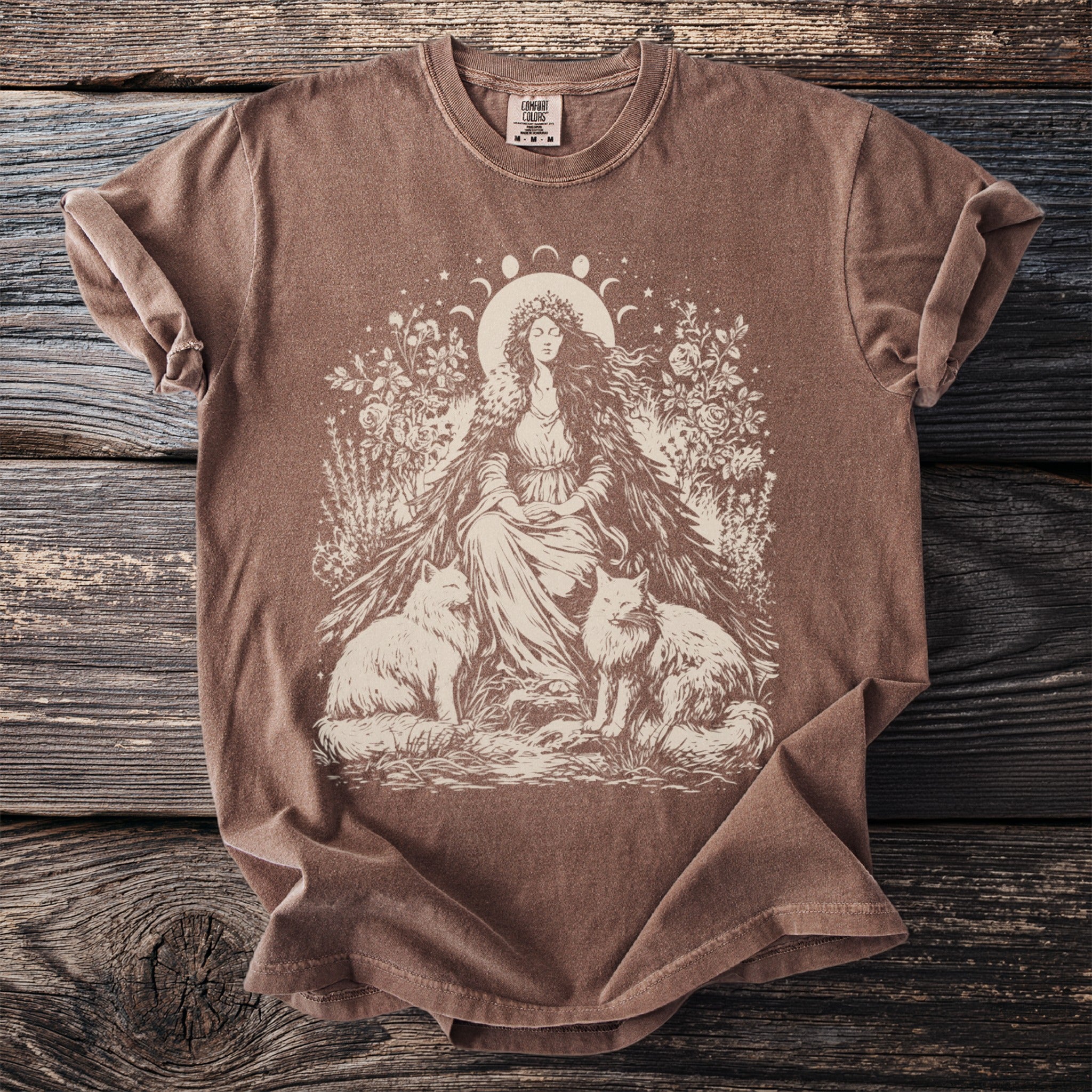 Brown t-shirt with cream graphic of woman, two foxes, and celestial moon phases.