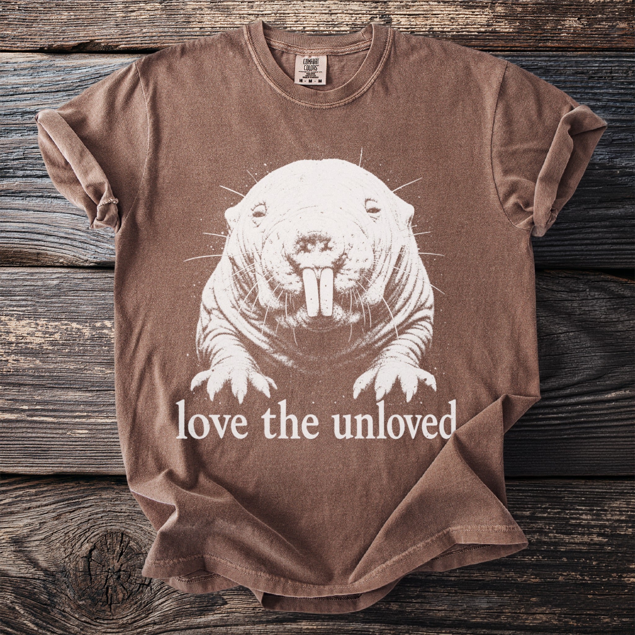 Brown t-shirt with a white drawing of a mole rat and the text "love the unloved".