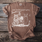 Brown t-shirt with "local cryptid support group" text and raccoon, opossum, cat, bat, and frog illustration.