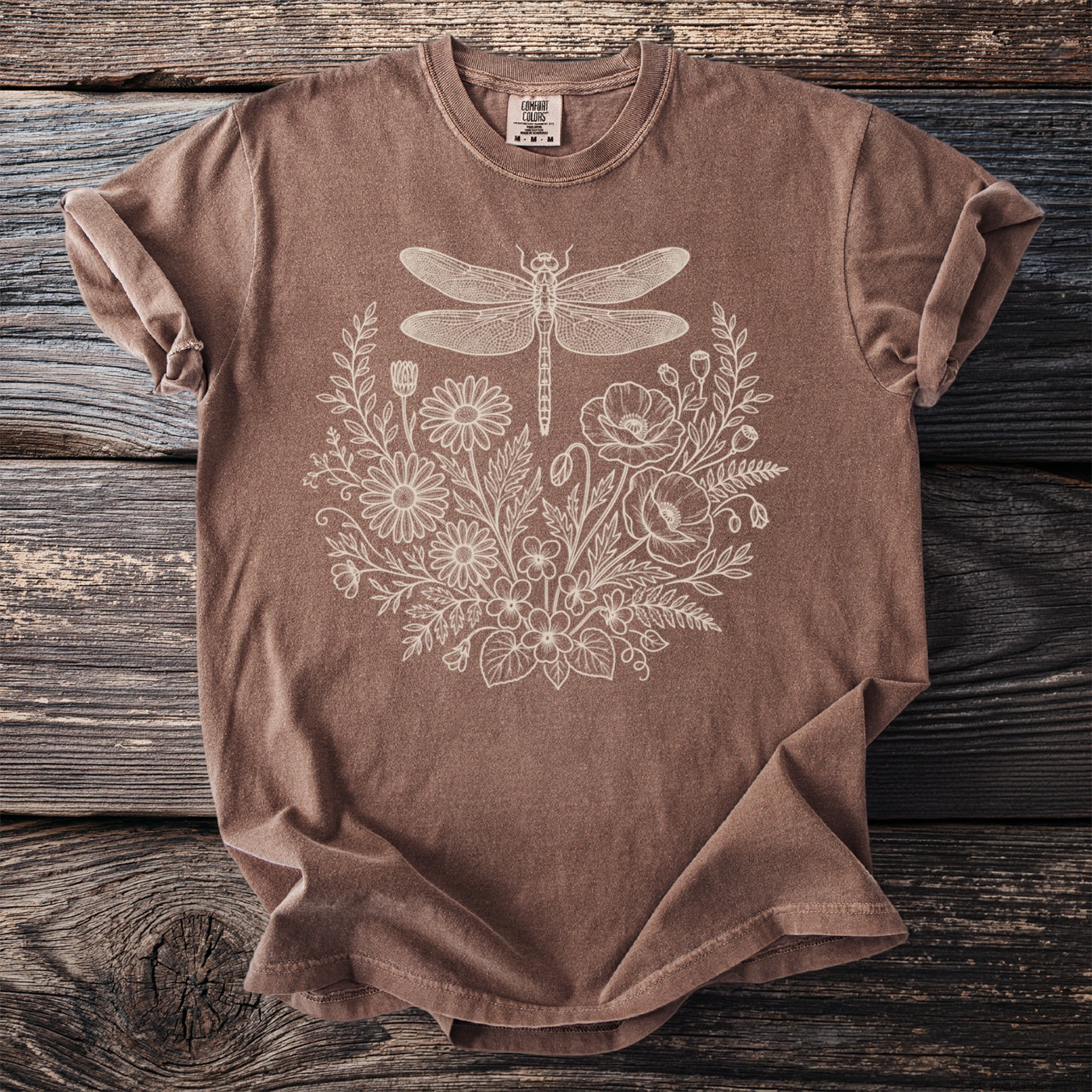 Brown t-shirt with cream dragonfly and floral sketch design on front.