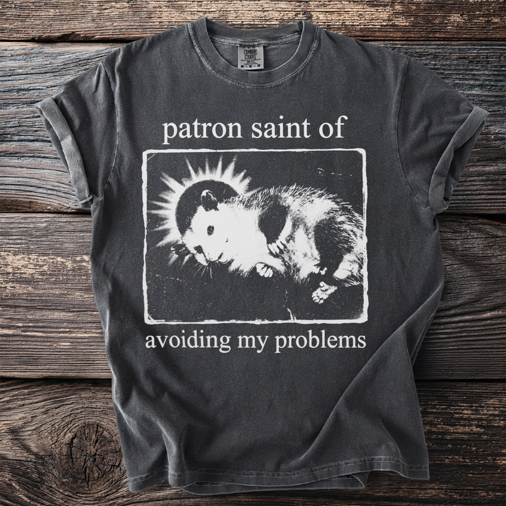 Dark gray t-shirt with "patron saint of" and an opossum graphic: "avoiding my problems".