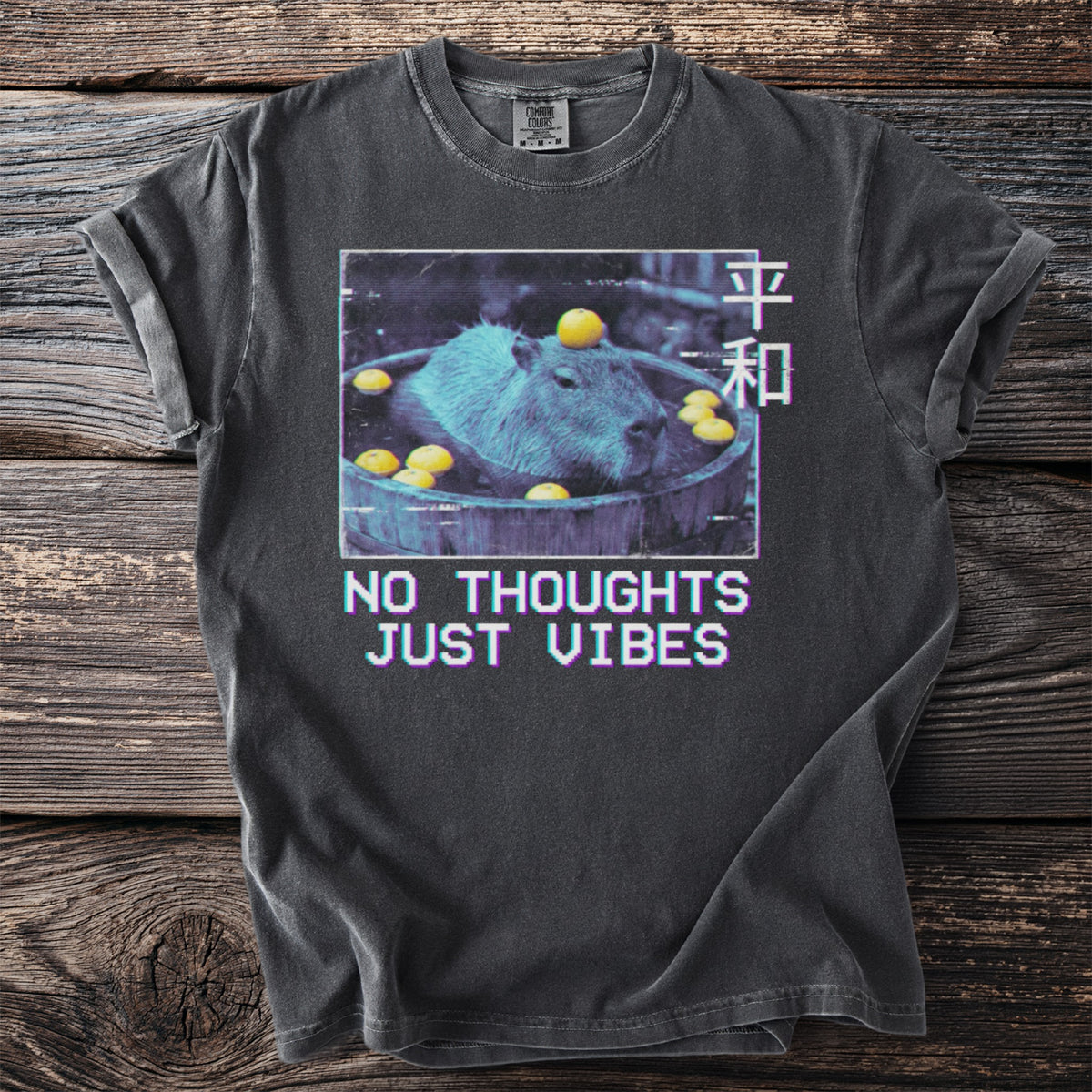 Dark t-shirt with capybara bathing in citrus fruit and text "NO THOUGHTS JUST VIBES".