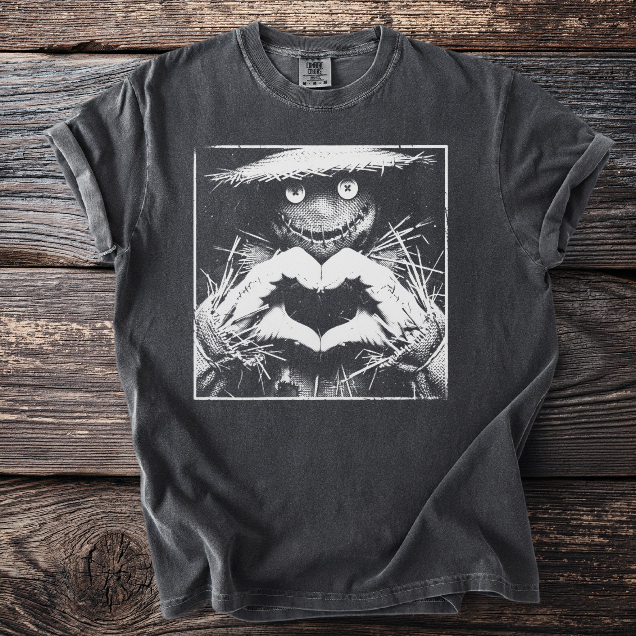Dark gray t-shirt with a black and white graphic of a scarecrow making a heart shape with its hands.