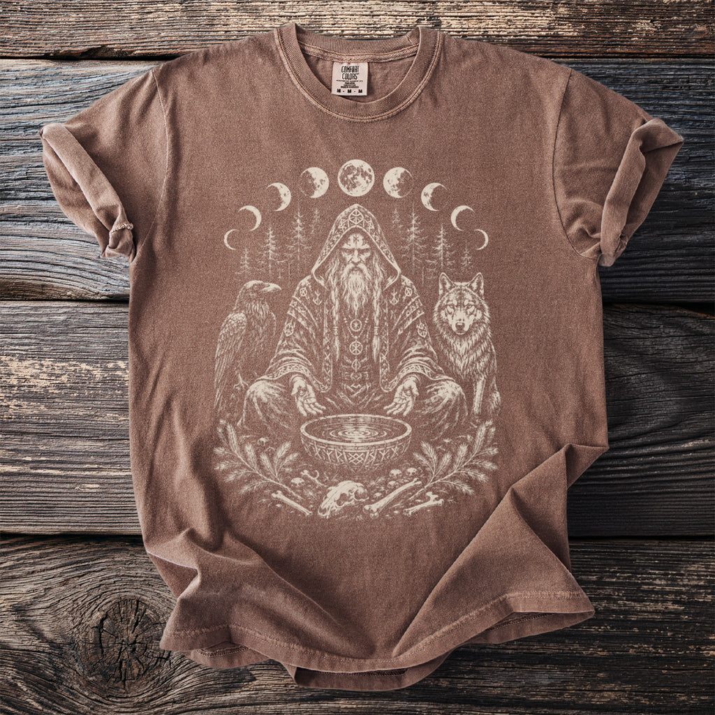 T-shirt featuring a central shamanic figure, wolf, raven, moon phases, and woodland elements.