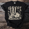 Black t-shirt with a linocut style print of a fox and raven among birch trees.