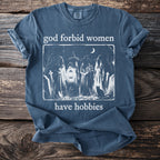 T-shirt with "god forbid women have hobbies" text and witch illustration.