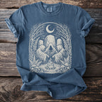 Blue t-shirt with a graphic of three hooded figures around a campfire under a moon.