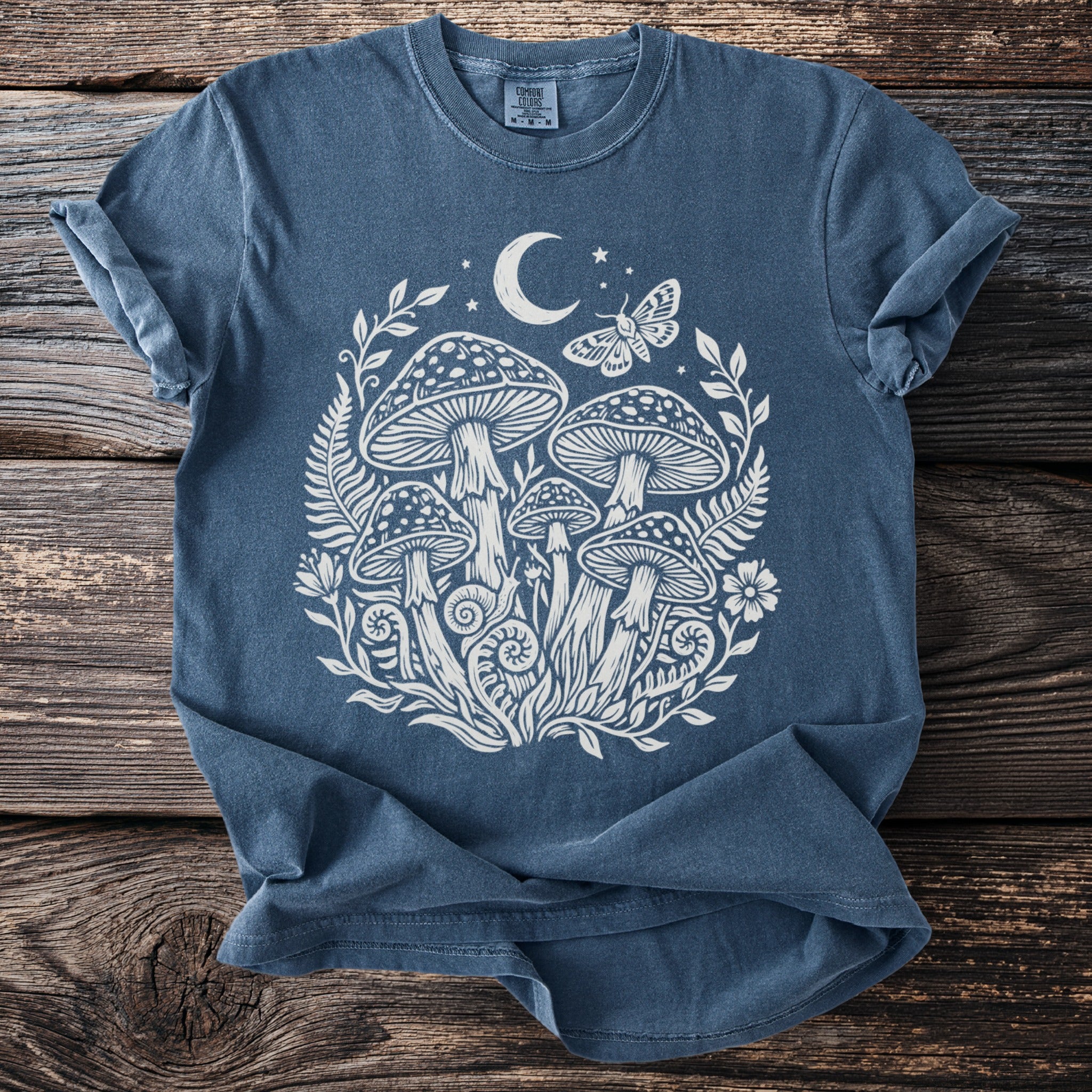 Blue t-shirt with white mushroom, moon, stars, and butterfly graphic.