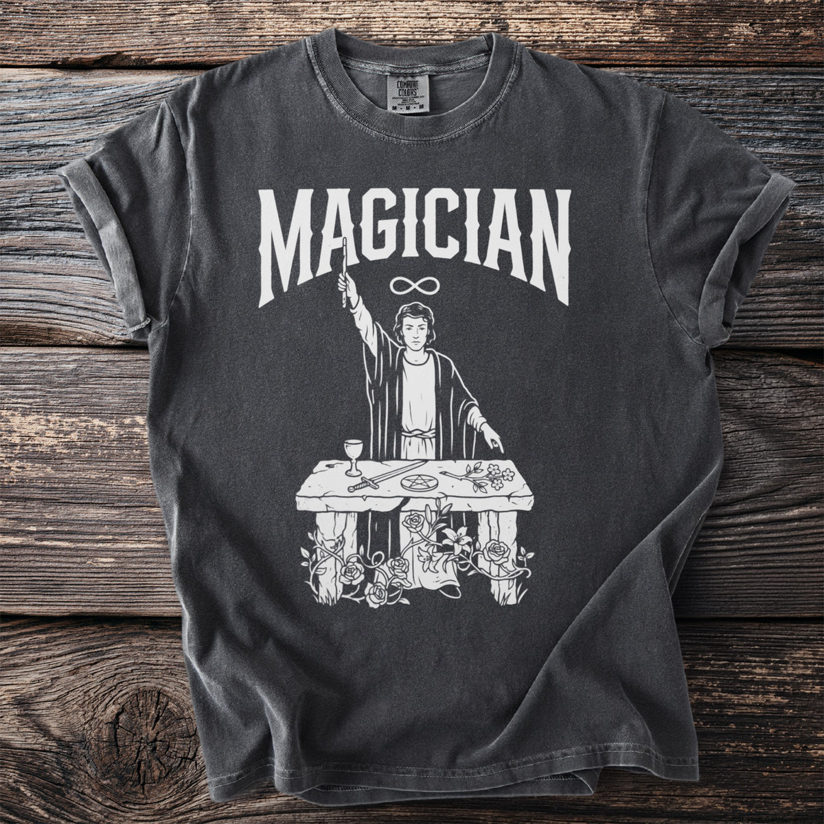 Dark gray t-shirt with "Magician" text and a mystical figure over a table.
