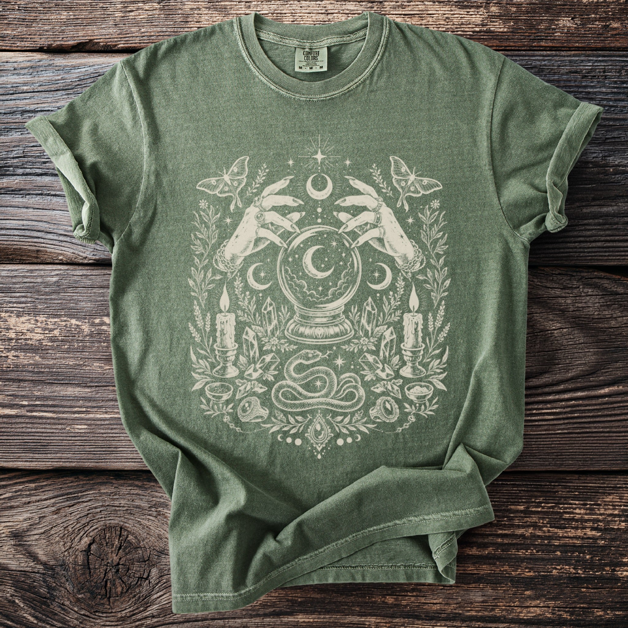 Green t-shirt with a white mystical graphic of hands holding a crystal ball.