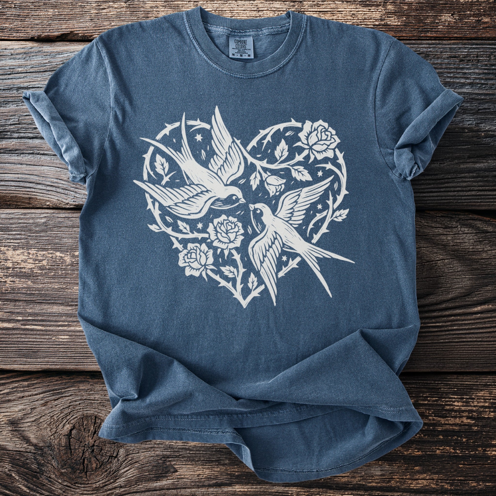 Blue t-shirt with white graphic of two birds and roses in a heart shape.