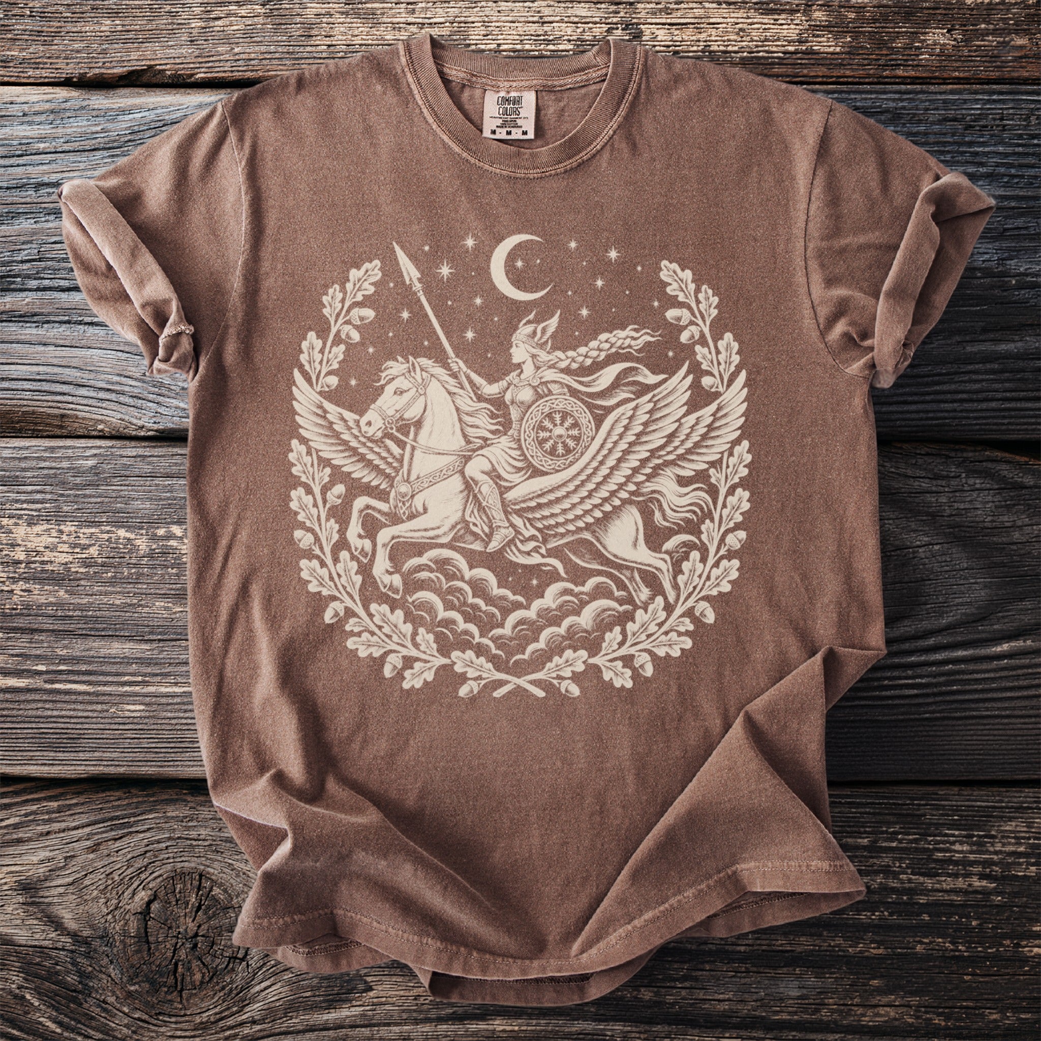 Brown t-shirt with cream graphic of Valkyrie riding Pegasus within oak leaf wreath and moon.
