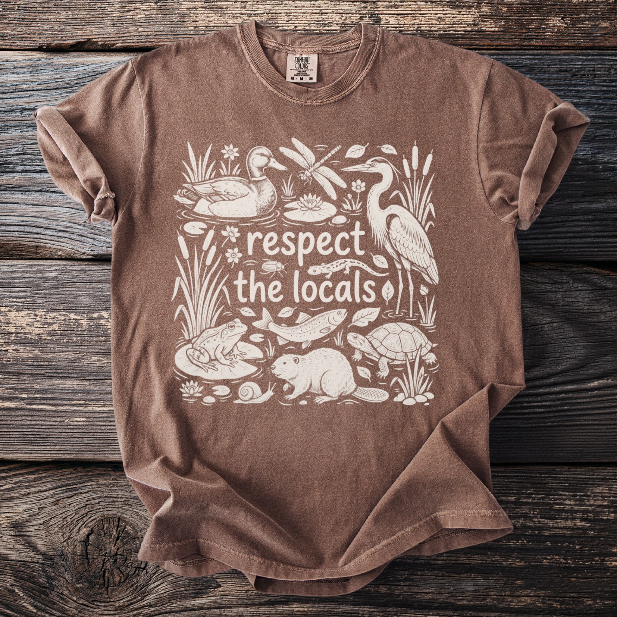 Brown t-shirt with white graphic of wetland animals and text "respect the locals".