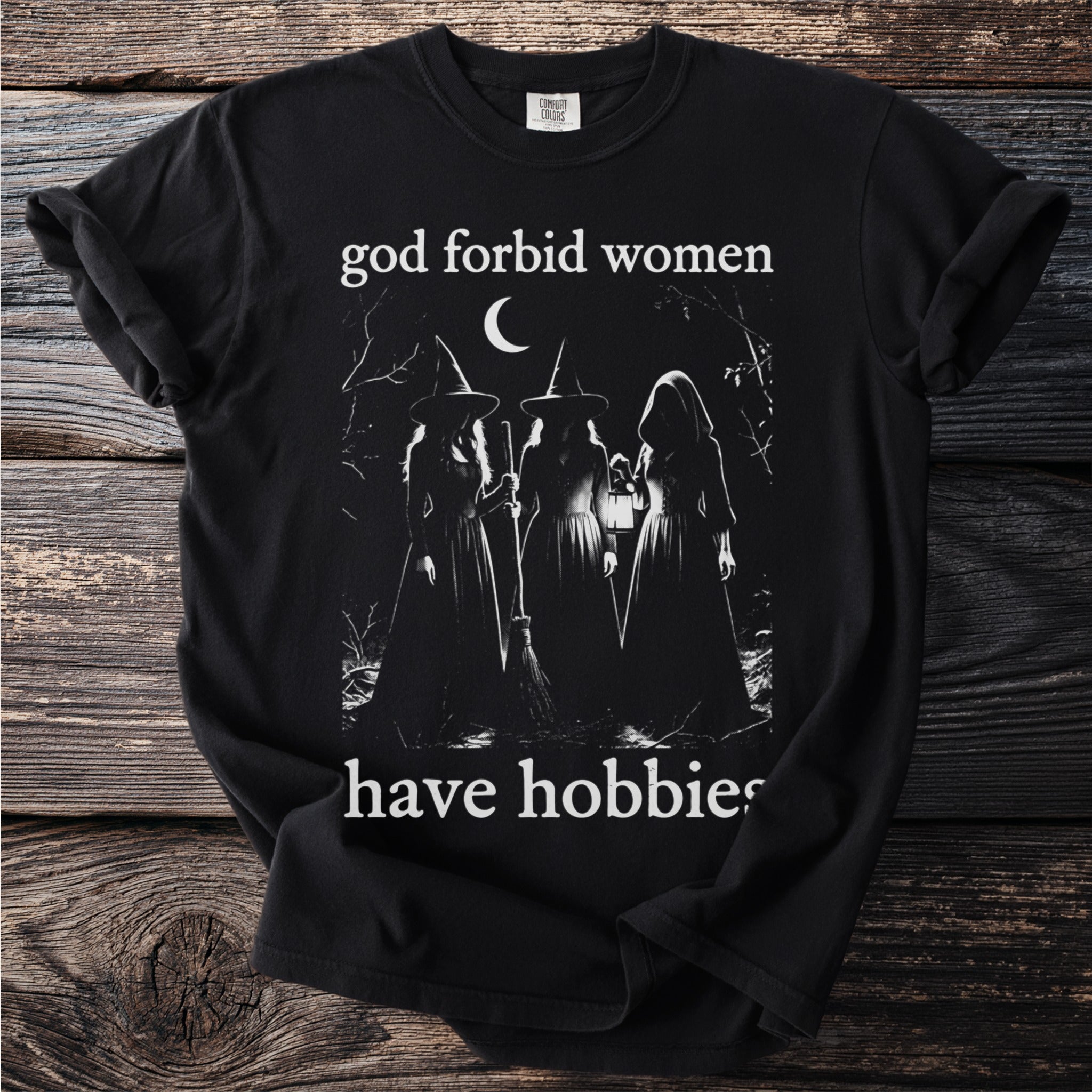 Black t-shirt with graphic of three witches and text "god forbid women have hobbies".
